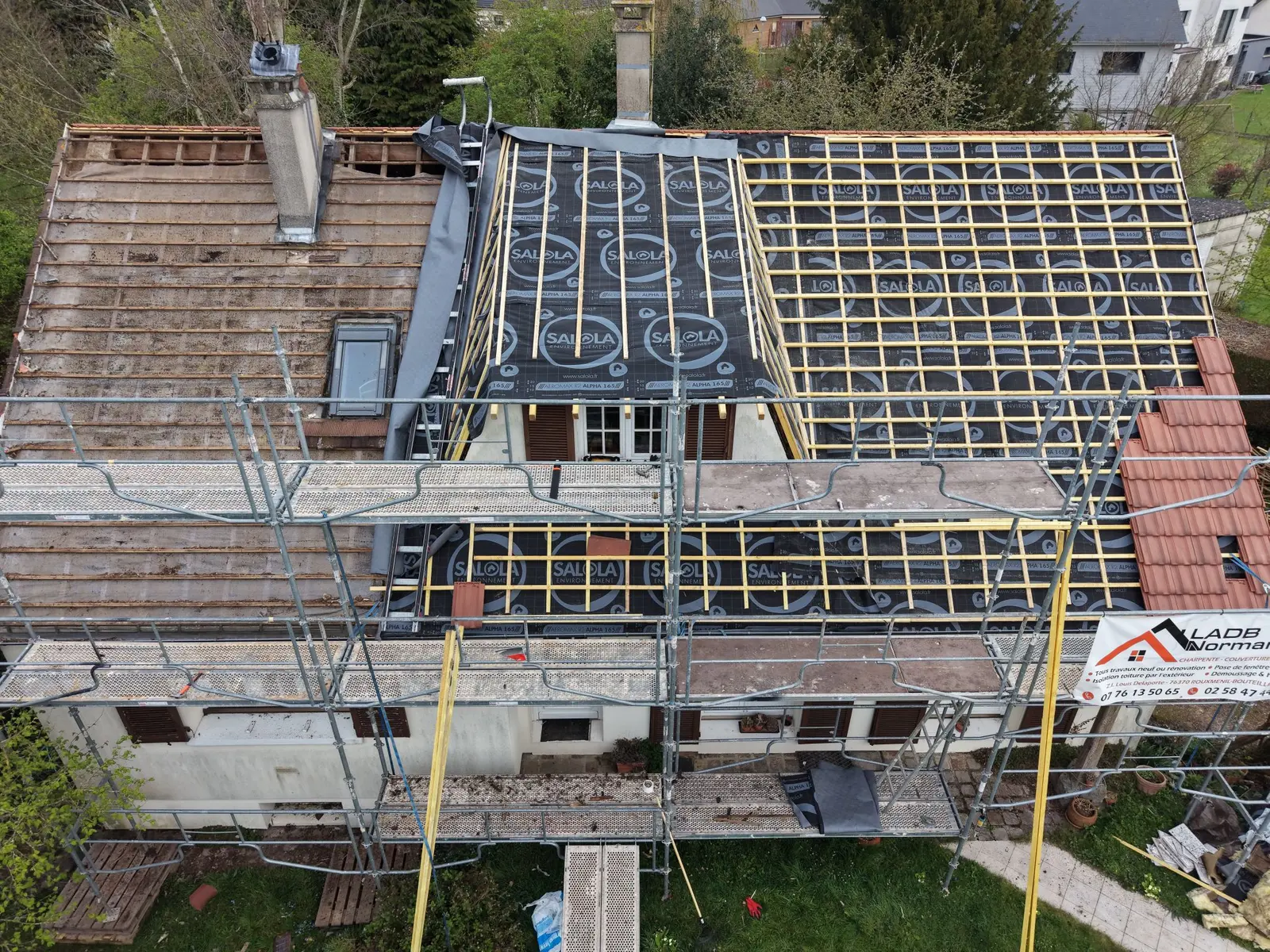 Vue du chantier avec une partie de la couverture déposée, un écran de sous-toiture et des liteaux.